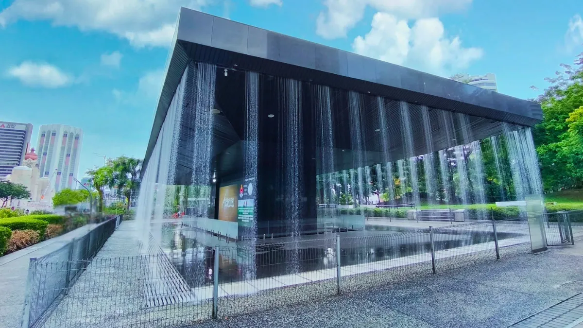 Jam Detik (Countdown Clock) A modern pavilion with water curtains flowing down its sides in a park
